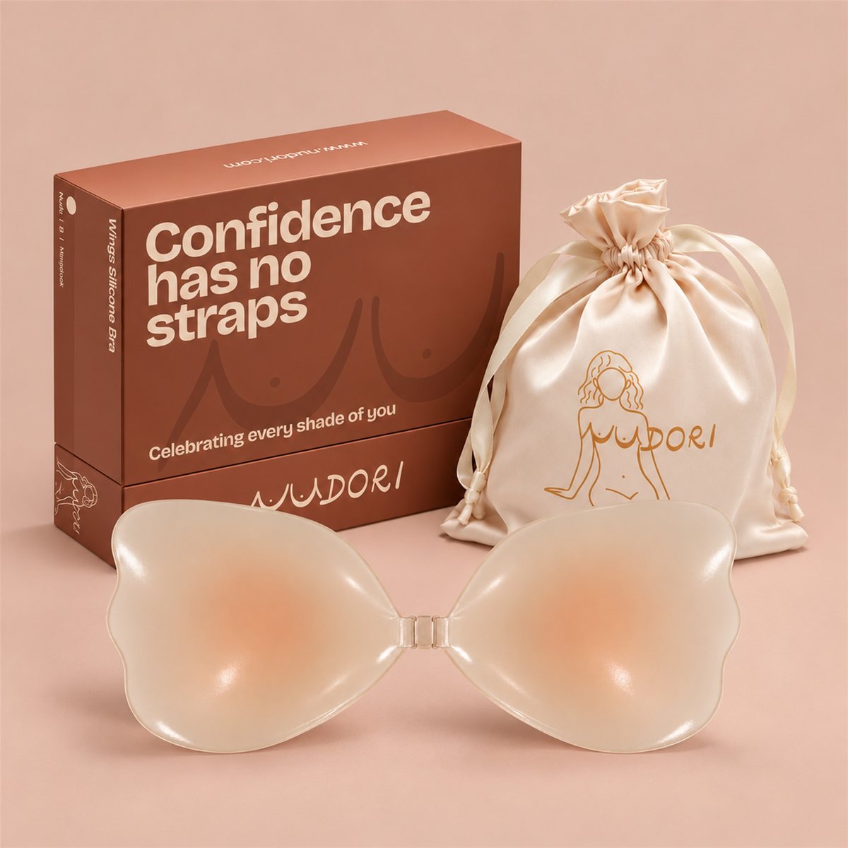 Nudori Wing Silicone Bra in Nude with the MagLock front clasp, box and satin pouch on a nude studio background.